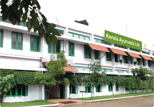 Exterior view of Kerala Ayurveda Ltd building with green windows and surrounding greenery.