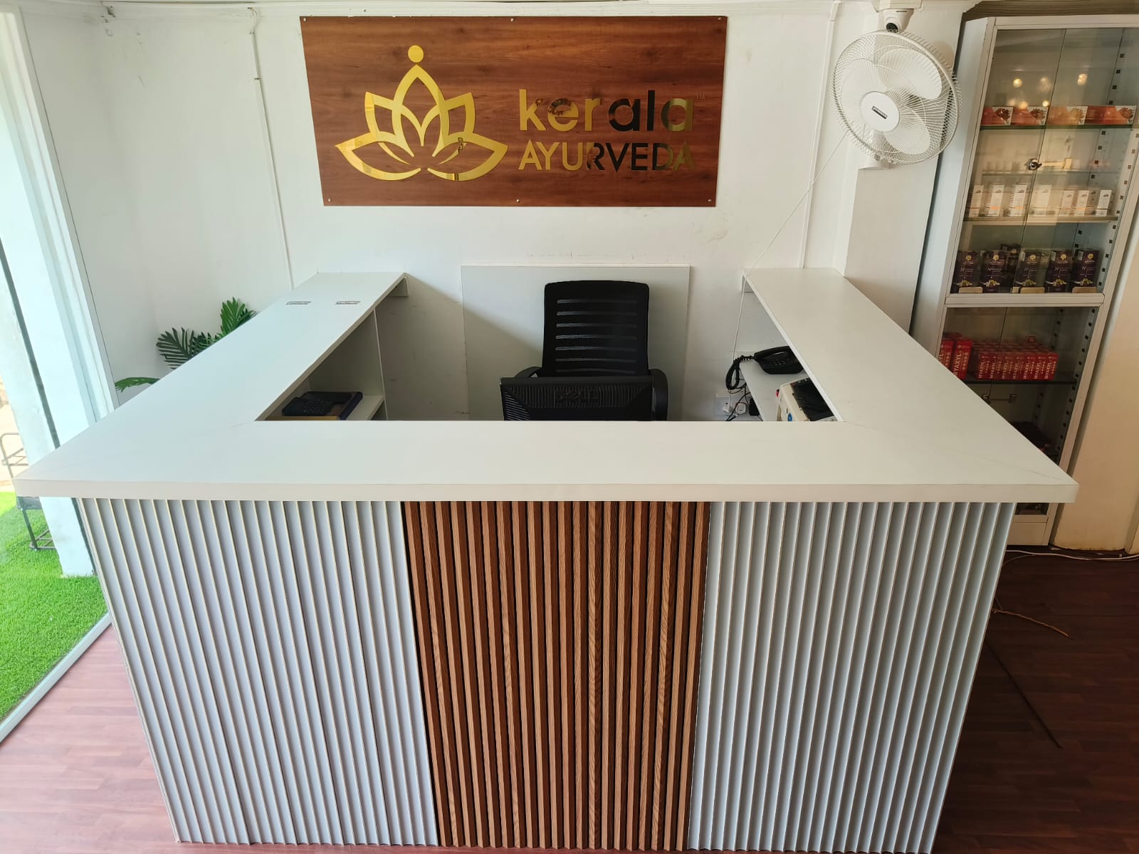 Reception area with a white countertop and a wooden sign that says "Kerala Ayurveda."