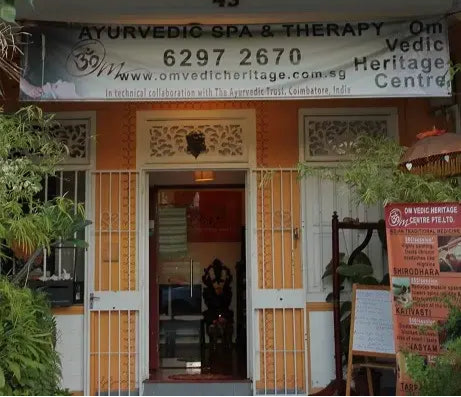 Entrance of Ayurvedic Spa & Therapy center with a sign displaying contact information and branding.