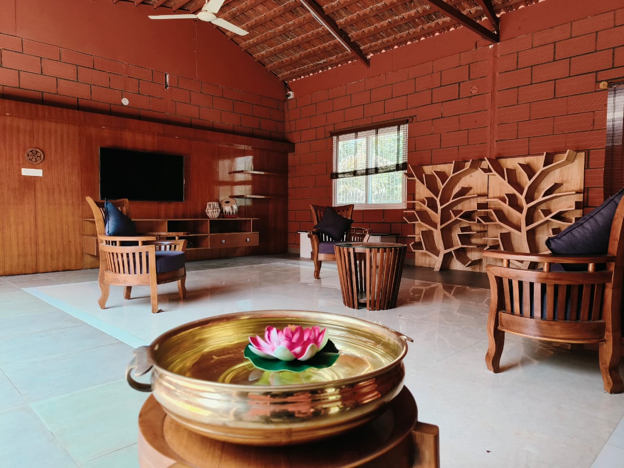 A cozy living area with wooden furniture, a TV, and a decorative bowl with a lotus flower.