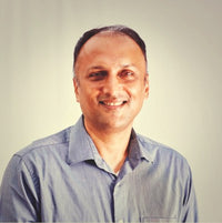 A smiling man in a light blue shirt poses against a neutral background.