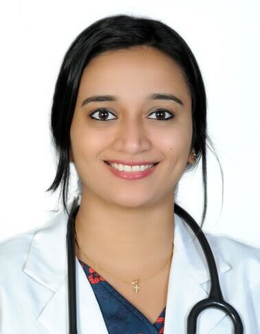 A smiling female doctor wearing a white coat and stethoscope, posed against a plain background.