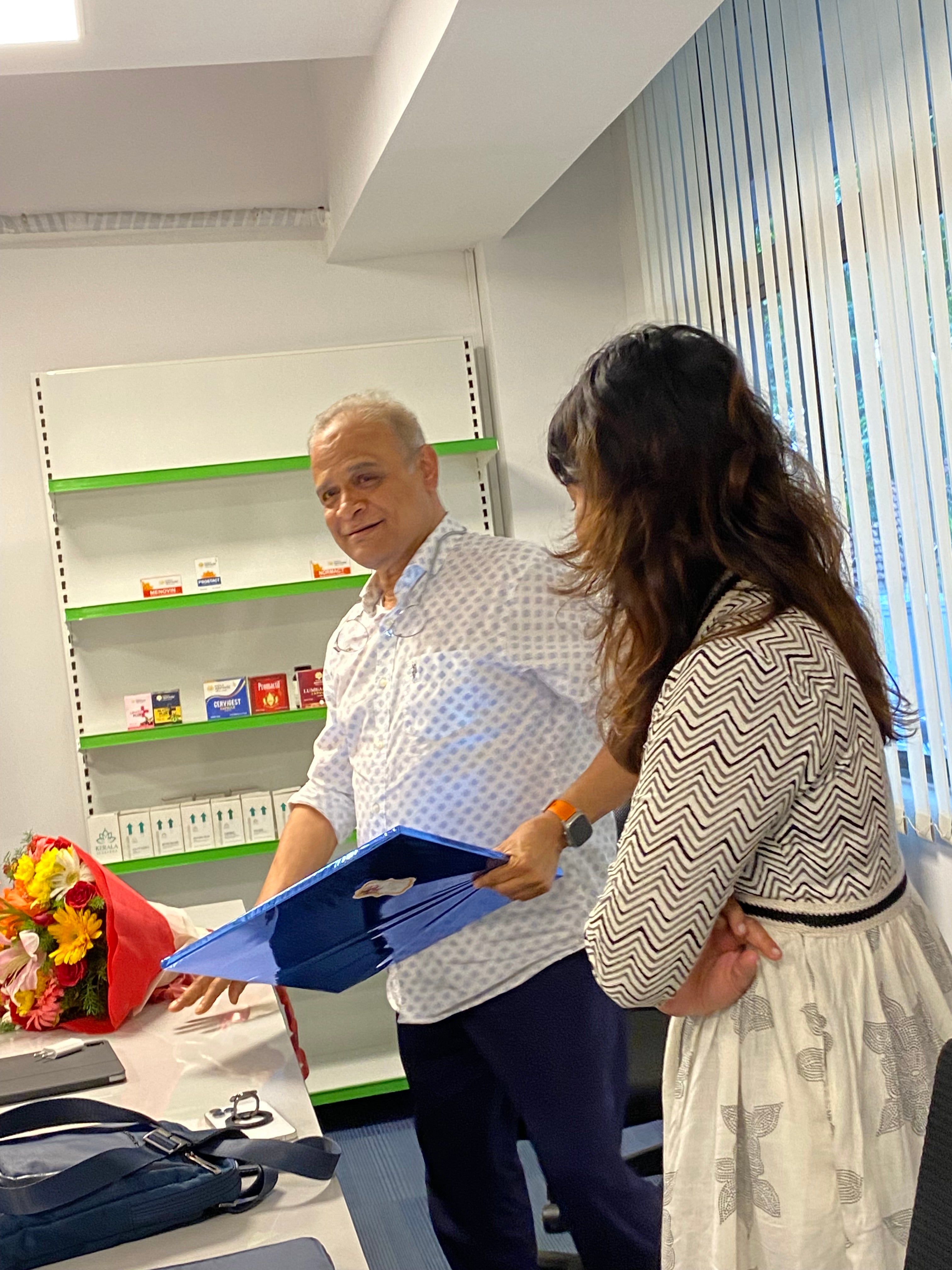 Two people in an office setting, one holding a binder and the other standing with their arms crossed.