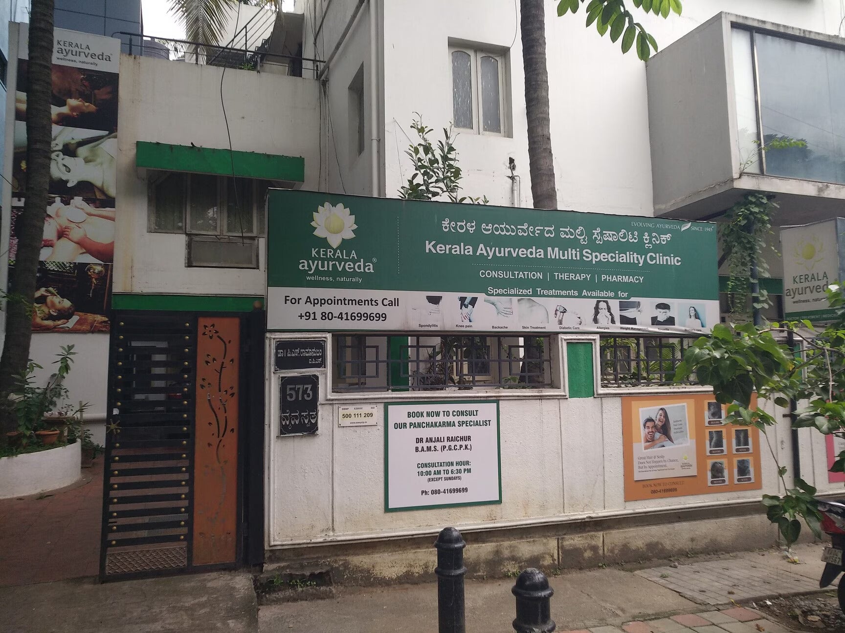 Kerala Ayurveda multi speciality clinic exterior with signboard and contact information for appointments.