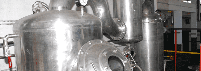 Stainless steel distillation equipment in an industrial setting.