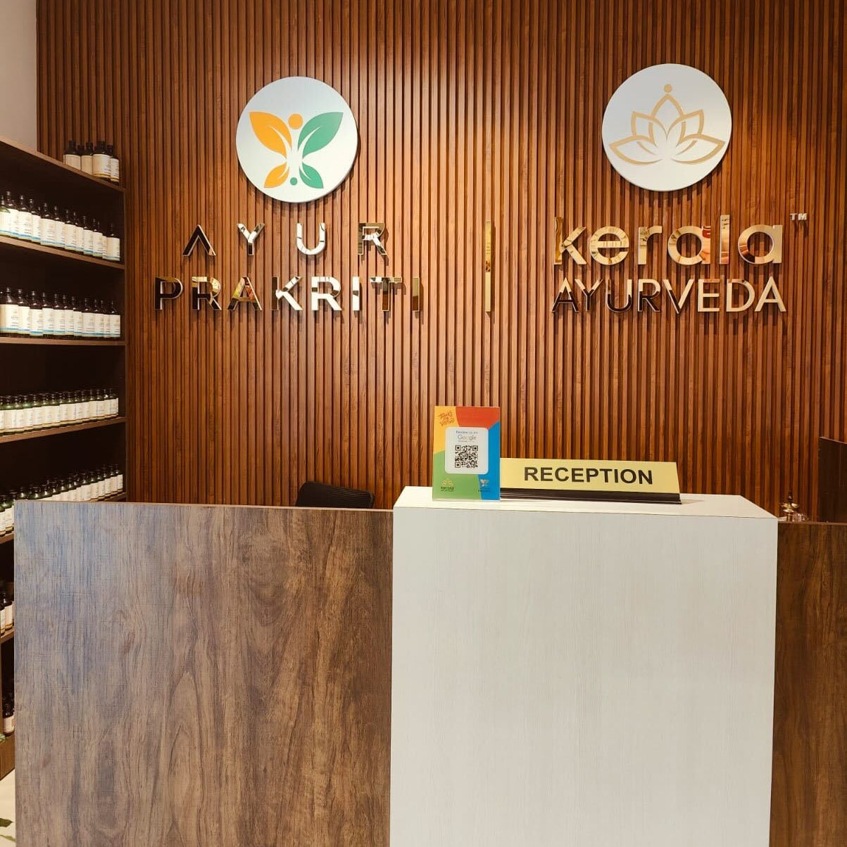 Reception area of an Ayurveda clinic with wooden paneling and branded signage.