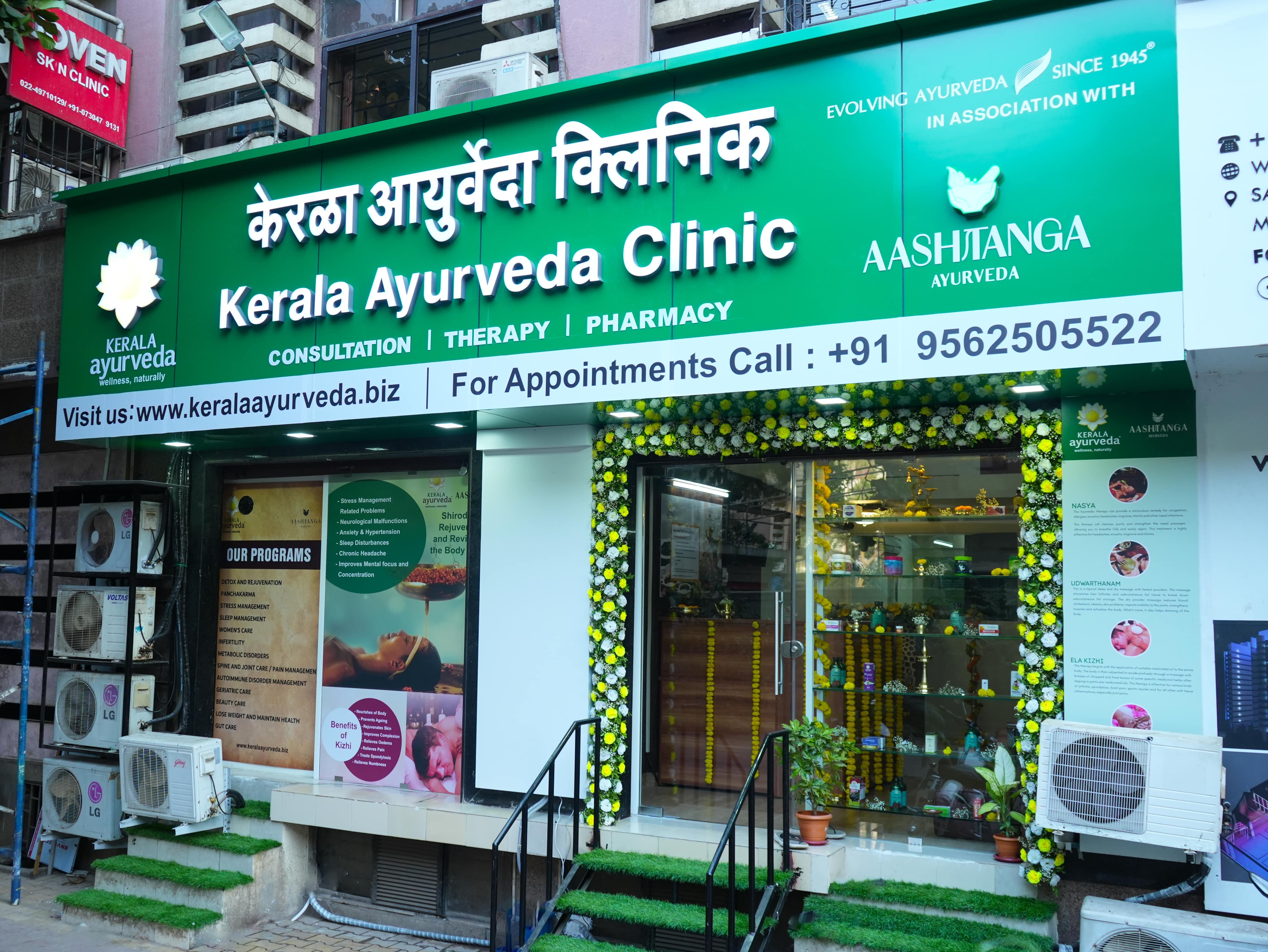 Kerala Ayurveda Clinic sign displaying services, contact information, and floral decorations.
